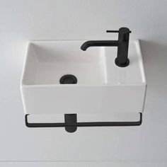 a white sink sitting on top of a wall next to a black faucet