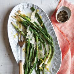 asparagus with parmesan cheese on a white plate next to a spoon