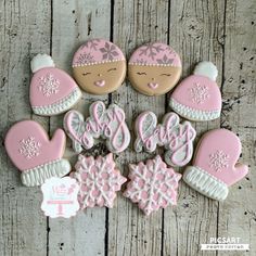 cookies decorated with pink and white frosting are arranged on a wooden surface, including one cookie that says it's cold