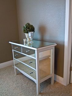 a small white table with two drawers and a potted plant on top of it