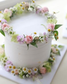 a white cake decorated with flowers and greenery