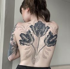 the back of a woman's body with tattoos on it