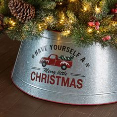 a christmas tree in a metal bucket with pine cones on the top and have yourself merry little christmas written on it