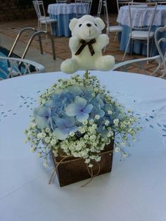 a teddy bear sitting on top of a table next to a bouquet of blue flowers