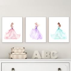 three watercolor princesses are displayed on the wall above a dresser in this room