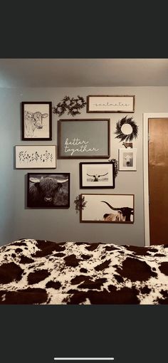 a bedroom with pictures on the wall and cow print bed spread in front of it