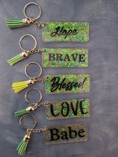 five keychains with words and tassels on them