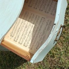 an old music box with sheet music in it's bottom compartment on the grass