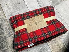 a red and black plaid blanket sitting on top of a wooden floor next to a brown tag