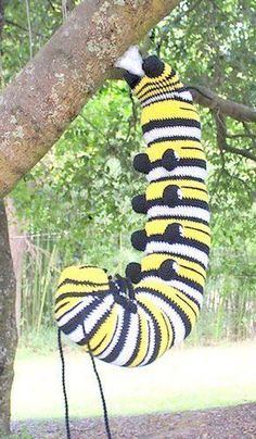 a stuffed caterpillar hanging from a tree branch