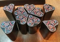 four wooden vases with designs on them sitting next to a black box filled with other items