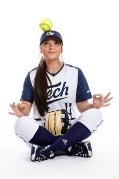 a woman sitting on the ground with a baseball in her hand