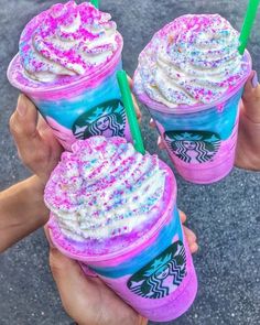 two people holding up colorful drinks with sprinkles