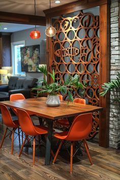 a dining room table with orange chairs in front of an iron screen and potted plants