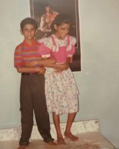 two young children standing next to each other in front of a poster on the wall