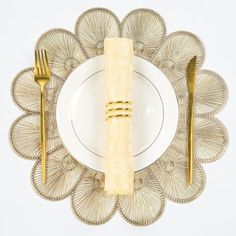 a white plate topped with a golden fork and knife next to a yellow napkin on top of it