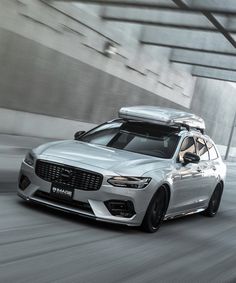 a silver car driving down a street next to a building