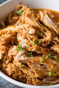 a bowl filled with shredded meat and garnished with parsley on the side