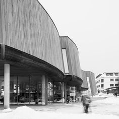 a black and white photo of people walking in front of a building with large windows