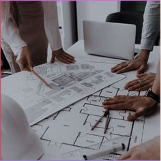 three people working on blueprints at a table