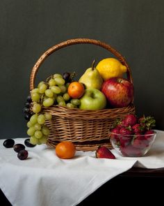 a wicker basket filled with fruit sitting on top of a white cloth covered table