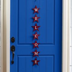 a welcome sign hanging on the front door of a blue house with red stars attached to it