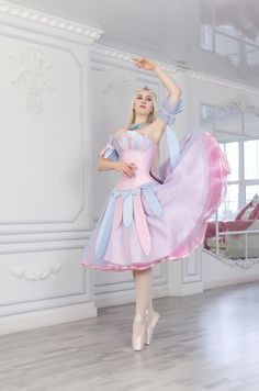 a woman in a pink and blue dress is posing for the camera while wearing ballet shoes