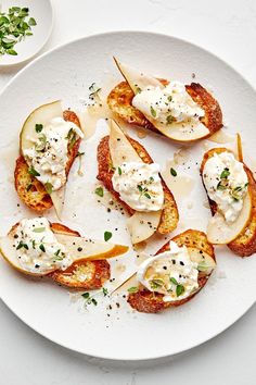 a white plate topped with slices of bread covered in cheese and herbs on top of it