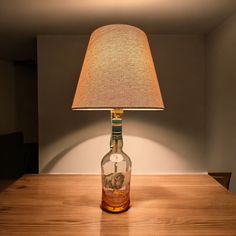 a lamp that is sitting on top of a wooden table next to a glass bottle