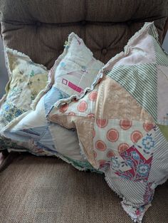 two pillows are sitting on the back of a chair, one is made out of patchwork fabric