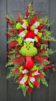 a christmas wreath with the grin face on it's front door, decorated with red and green ribbons