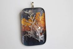 a glass pendant with an image of a bird and tree on it's side