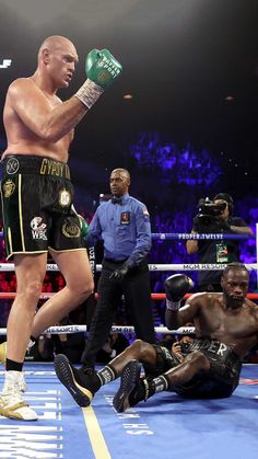 a man standing next to a referee in a boxing ring