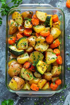 a glass dish filled with roasted vegetables and garnished with parsley on the side