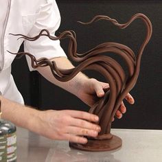 a person that is making something out of clay and some kind of chocolate thing on the table