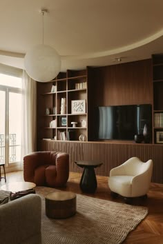 a living room filled with furniture and a flat screen tv mounted on a wall next to a window