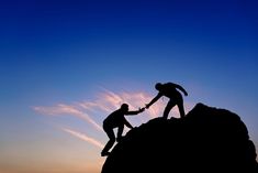 two people helping each other to climb up a mountain at sunset with the words social outlier above them