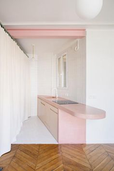 an empty kitchen with pink counter tops and white walls, along with wood flooring