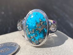 Make a statement with this stunning Persian Turquoise oval cabochon ring! It has been set with a generous 925 Sterling Silver surround and adjustable domed band, which is very comfortable to wear. This Persian Turquoise oval cabochon displays a gorgeous deep colour with sparkling Pyrite inclusions. Originally called 'piruzeh' in Persian, the gem has spiritual value in Persian culture is such that its name carries the meanings of victory, triumph, and prosperity. Turquoise is an opaque, blue-to-g Oval Turquoise Chrysocolla Ring In Silver, Oval Silver Chrysocolla Turquoise Ring, Persian Turquoise Ring, Turquoise Jewellery, Turquoise Statement Ring, Droplet Earrings, Persian Turquoise, Persian Culture, Ring Turquoise