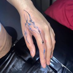 a person's hand with a blue ink tattoo on their left thumb and fingers