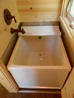 a small bathroom with a sink and window in the back wall, along with wood flooring