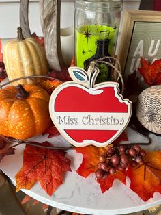 an apple sign sitting on top of a table surrounded by autumn leaves and pumpkins