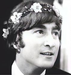 a young man wearing a flowered headband and looking off into the distance with his eyes wide open