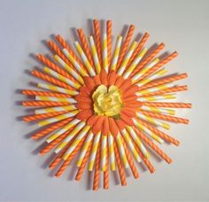 an orange and yellow sunburst made out of toothpicks on a white surface