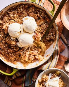 an apple crisp pie with ice cream on top in a green skillet next to two bowls