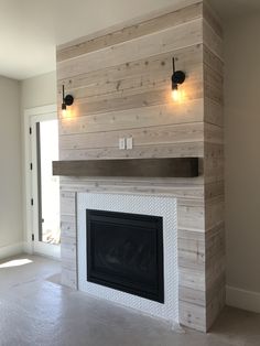 an empty living room with a fireplace and two lights on the side of the wall