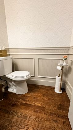 a white toilet sitting in a bathroom next to a wooden floor