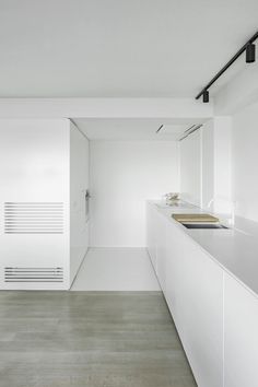 an empty kitchen with white walls and flooring