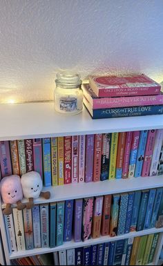 a book shelf filled with lots of books next to a lit candle and glass jar