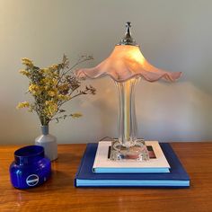 a table lamp sitting on top of a blue book next to a vase with flowers